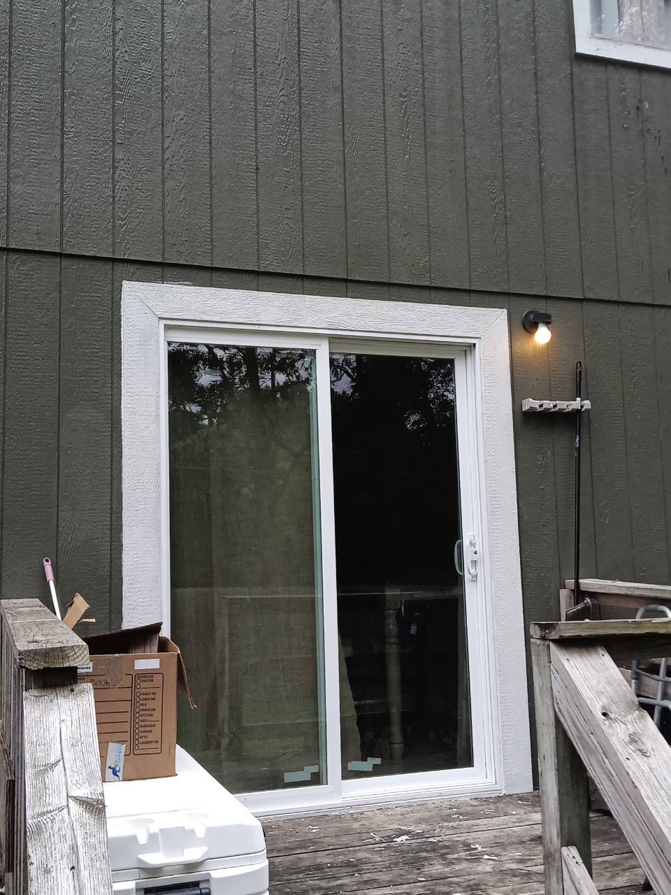 Completed white sliding patio door installed in dark exterior siding