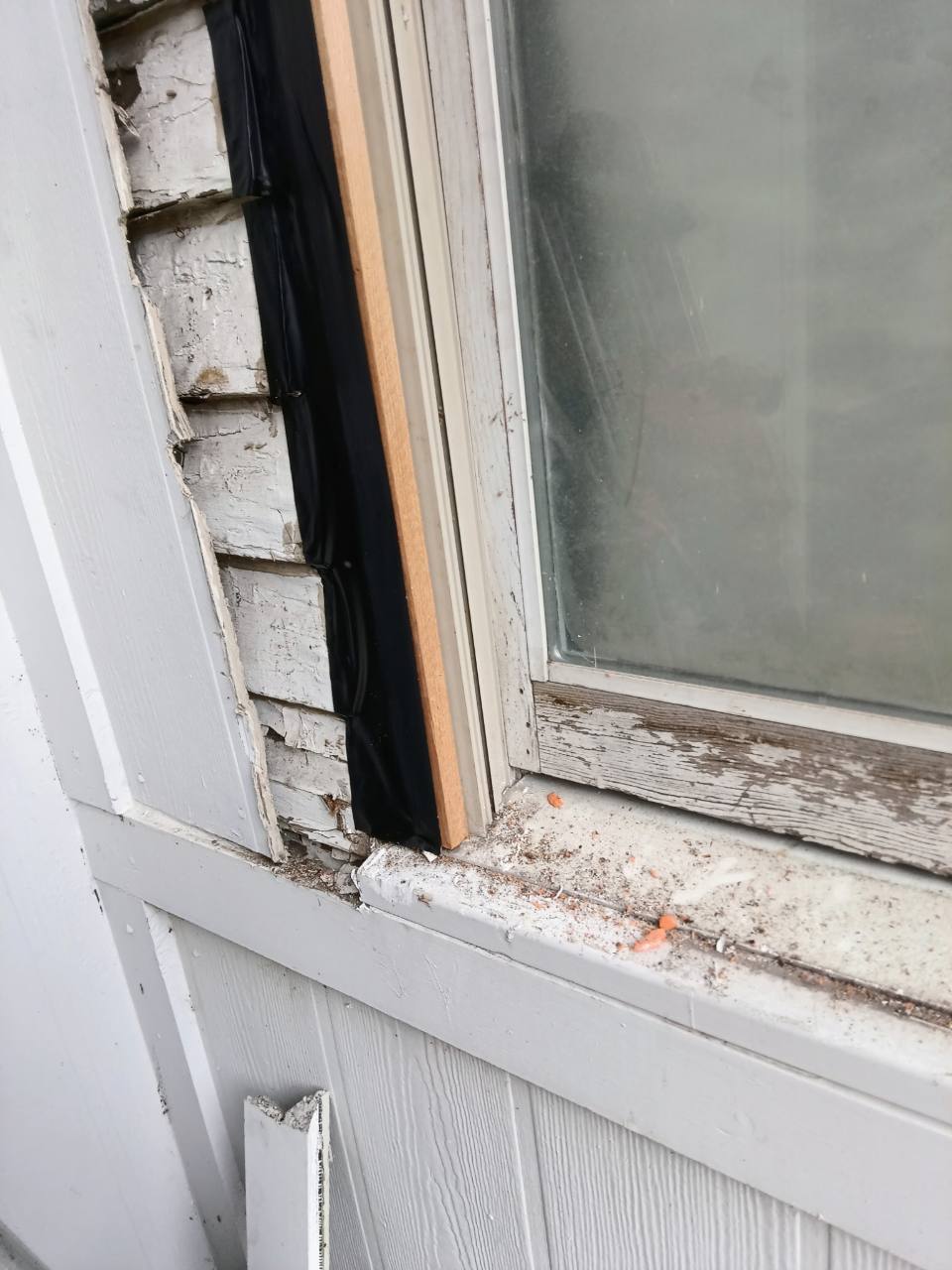 Close view of left-side weatherproofing and new wood trim beside the window